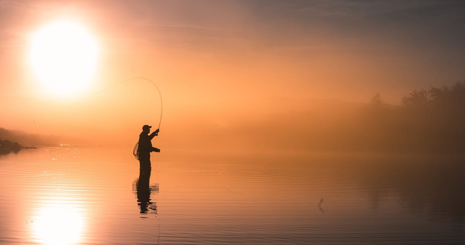 Idyllinen siluetti mies kalastaa vastavalo